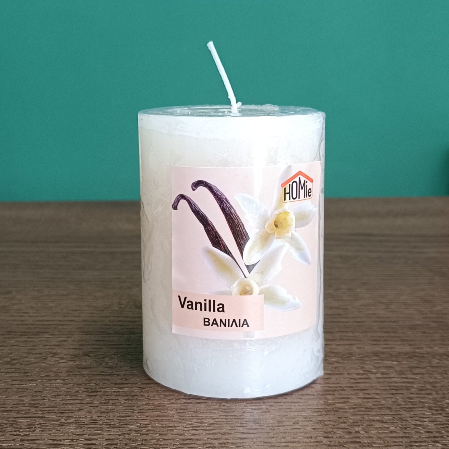 Aρωματικό κερί κολώνα Vanilla Φ7x10cm μετωπική όψη σε πράσινο φόντο που αναδεικνύει την ετικέτα - VassoHome