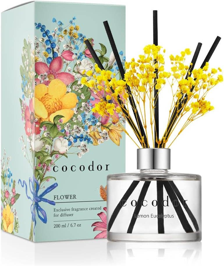 Αρωματικό χώρου Cocodor Flower Diffuser με κίτρινα λουλούδια, μαύρα sticks και γαλάζια συσκευασία με λουλουδάτα σχέδια σε λευκό φόντο - VassoHome