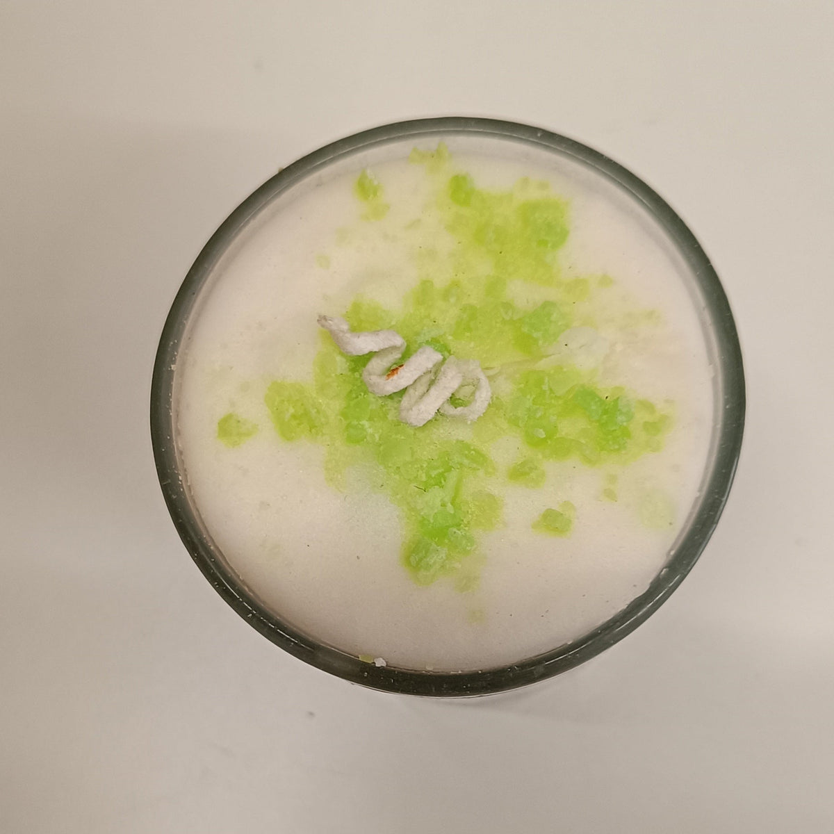 Top view αρωματικού κεριού Vanilla & Lime που αναδεικνύει την πράσινη lime διακόσμηση και τον φυτίλι σε λευκό φόντο - VassoHome